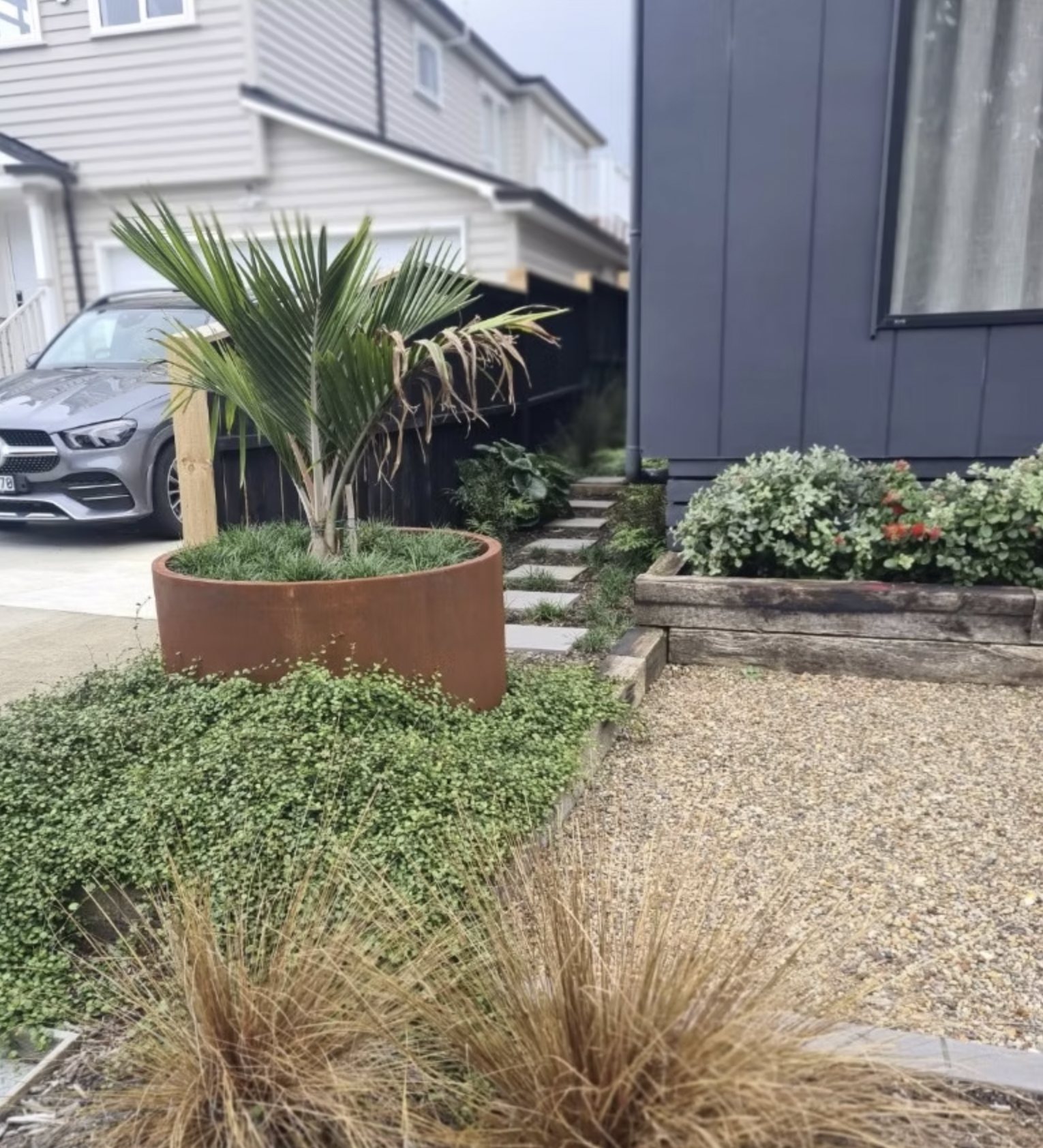 Front garden with a corten circular planter and palm
